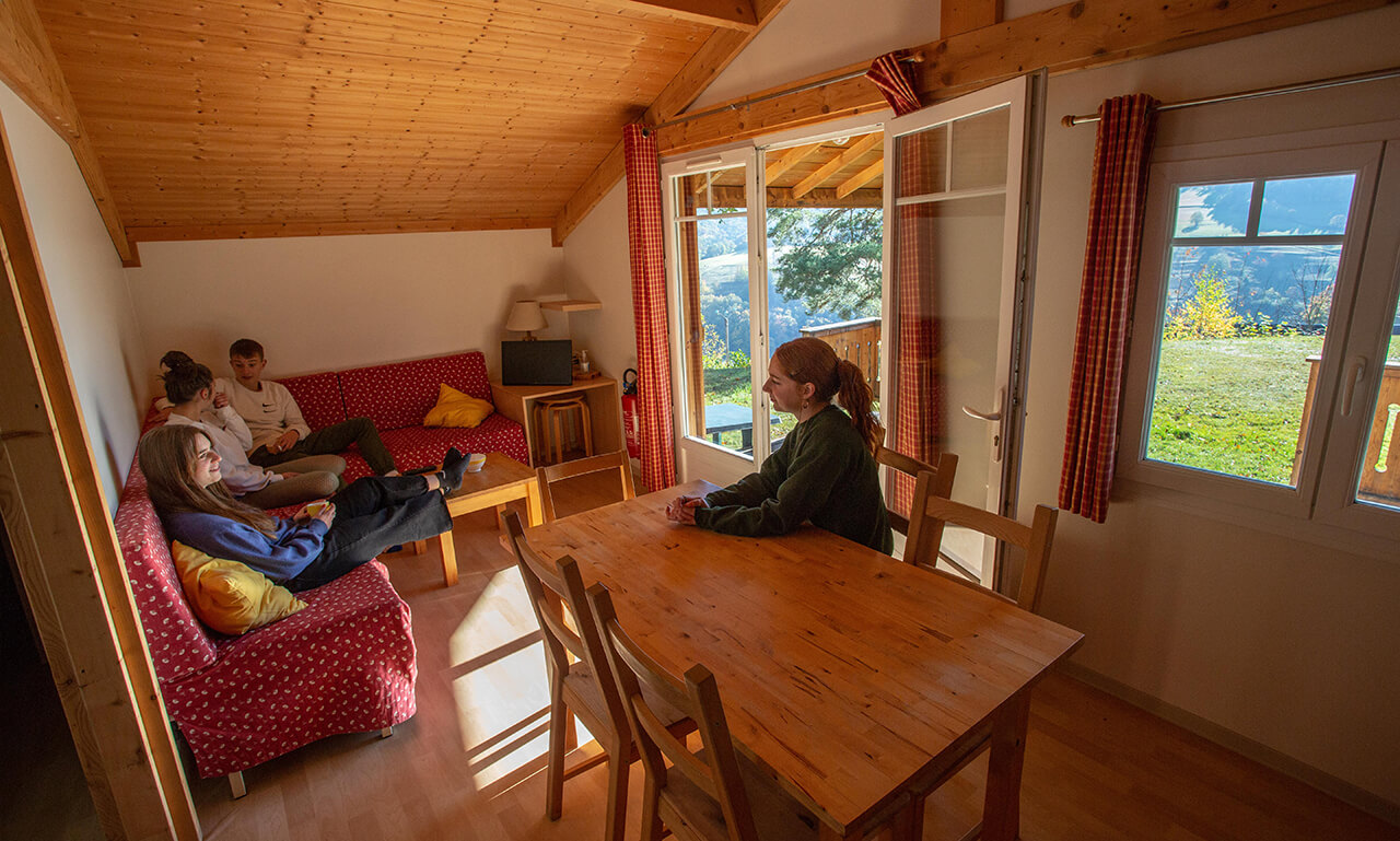 Coin repas et coin salon du chalet CHARLAY 21 en location au camping Lefébure en Alsace à Orbey